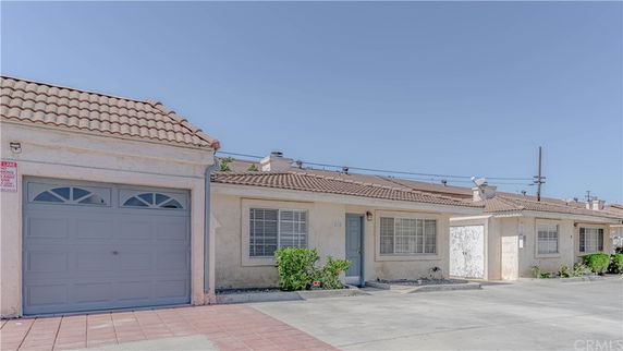Front view of single-story houses with garages and tiled roofs.
