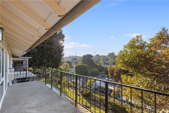 View from a balcony overlooking a suburban area with trees and houses.