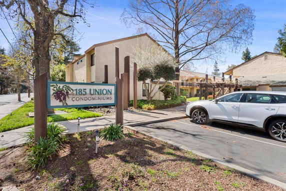 Front view of condominium buildings with a parking area and sign displaying '185 Union Condominiums'.