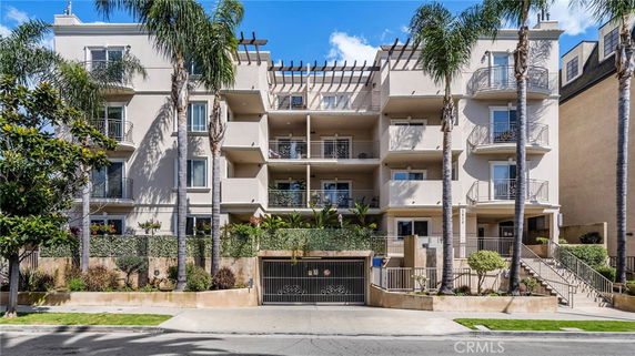 Front view of a multi-story residential building with balconies and gated entrance.