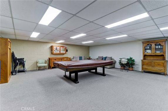 Indoor recreation room with a covered pool table, seating area, and storage furniture.
