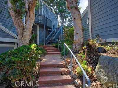 Front view of a house with a staircase and trees.