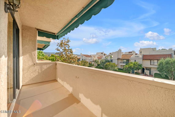 Balcony view of a residential neighborhood with multiple houses and trees under a clear blue sky.