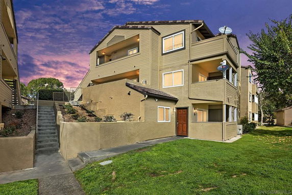 Front view of a multi-story apartment building with balconies and a sloped walkway.
