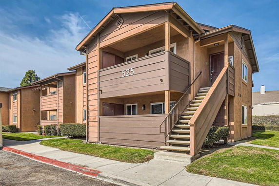 Front view of a two-story apartment building with exterior stairs and balconies.