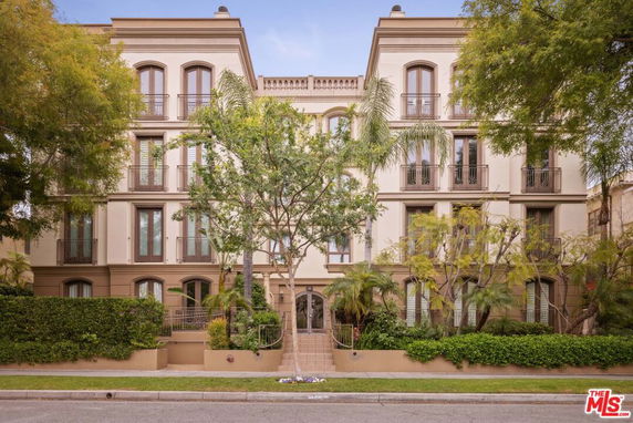 Front view of a multi-story building with arched windows and landscaped entrance.