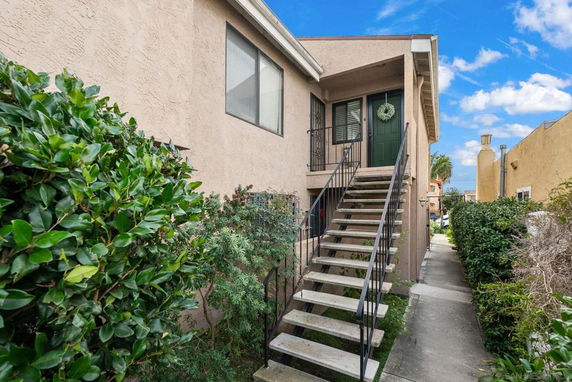Front view of a two-story house with an external staircase leading to the upper floor.