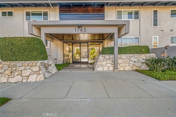 Front view of a multi-story building entrance with stone walls and glass doors.