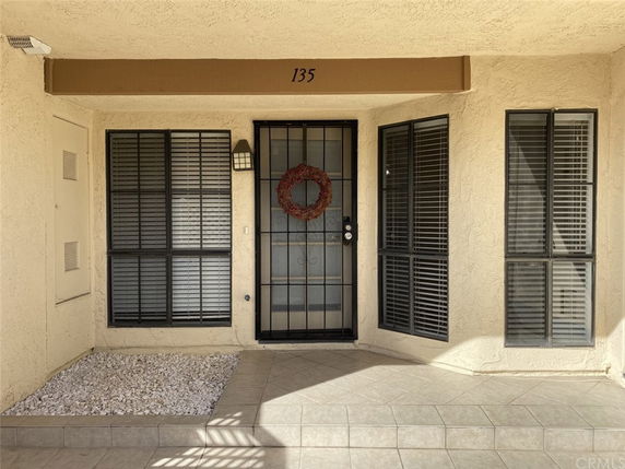 Front view of a building entrance with a metal security door and windows with shutters.