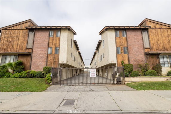 Front view of a multi-story residential building with a gated entrance.