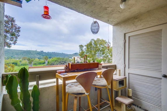 Balcony with seating overlooking a scenic landscape with hills and trees.