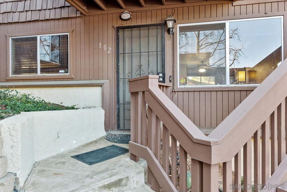 Front view of a house with wooden exterior and stairs leading to the entrance.