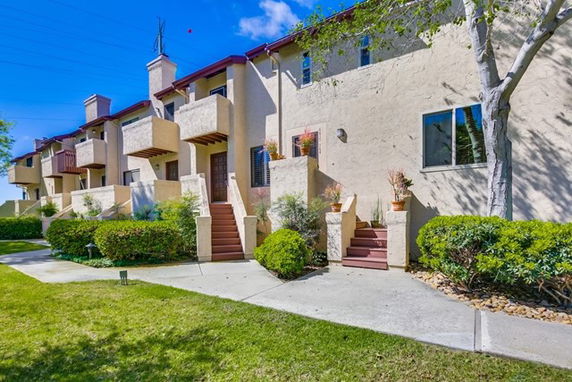 Front view of a multi-story townhouse building with stairs leading to each entrance.