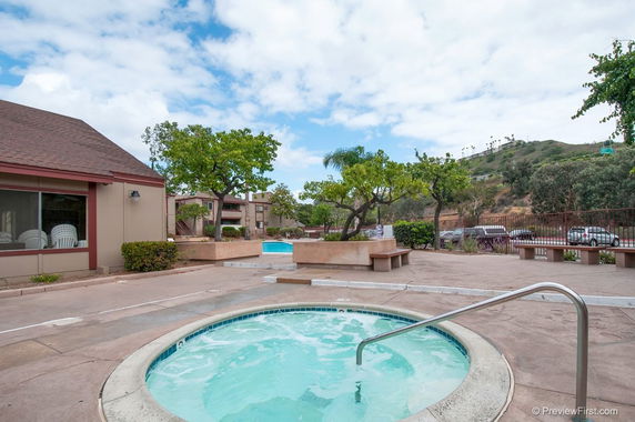 Outdoor area with a round hot tub and rectangular swimming pool surrounded by trees.