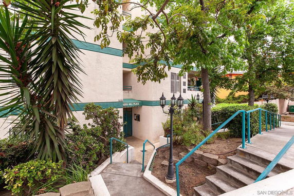 Front view of a multi-story building with stairs and greenery.