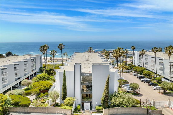 Front view of a large multi-story building with ocean in the background.