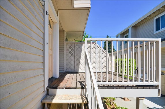 Front view of a house with a small wooden porch and railing.