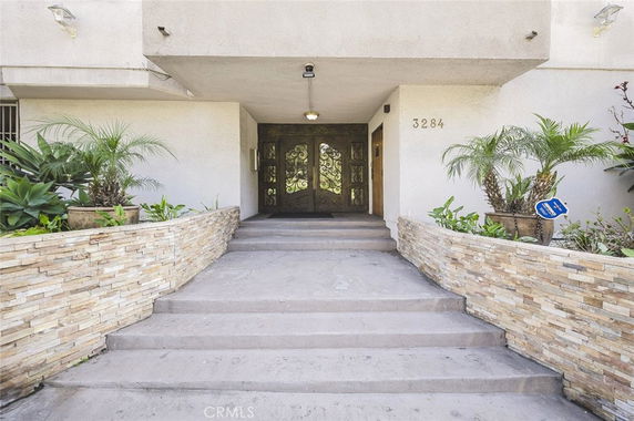 Front entrance view of a building with stone wall planters and decorative doors.