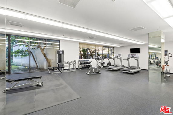 Indoor gym area with exercise equipment including treadmills and weights.