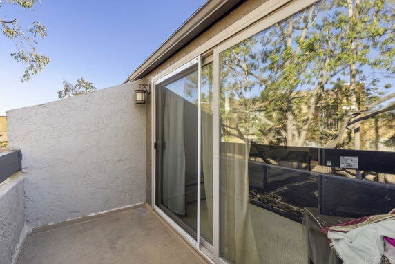 View of a rooftop with a sliding glass door and outdoor wall lights.