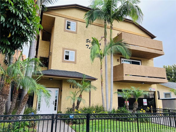 Front view of a multi-story residential building with balconies and a gated entrance.