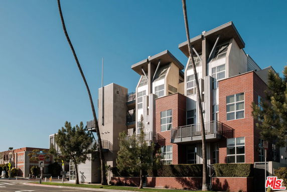 Front view of a modern apartment building with large windows and angular roof structures.