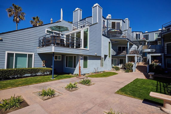 Front view of a multi-story residential building with balconies and outdoor seating.