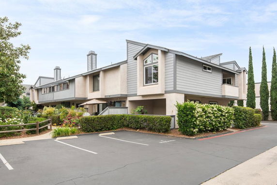 Front view of a modern two-story residential building with gray and beige siding.