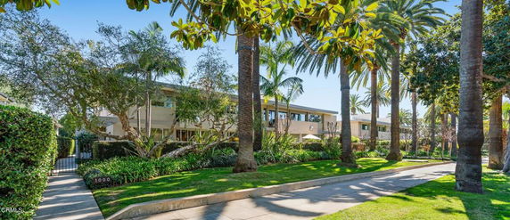 Front view of a multi-story building with large windows and surrounded by trees.