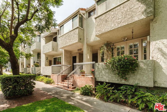 Front view of a multi-story residential building with balconies and greenery.