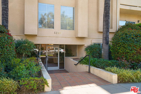 Front view of a multi-story building with a glass entrance and numbered address above.