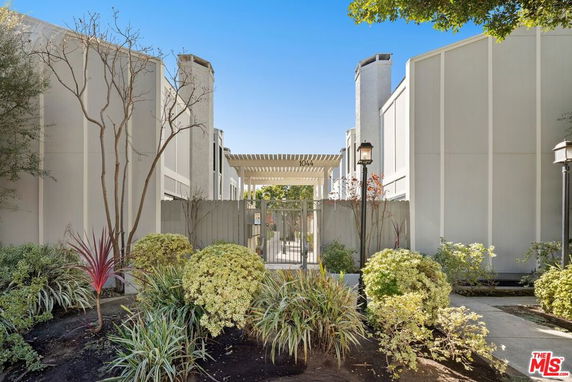 Front view of a modern building with a gated entrance and landscaped garden.