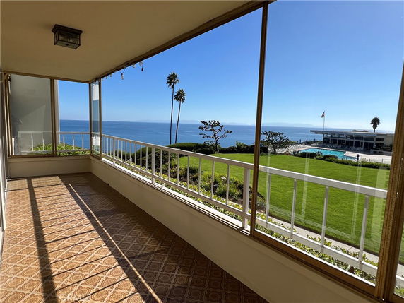 Panoramic view from a terrace overlooking the ocean and a landscaped lawn.
