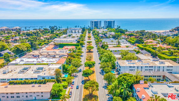 Panoramic aerial view of a coastal city with buildings and roads leading to the ocean.