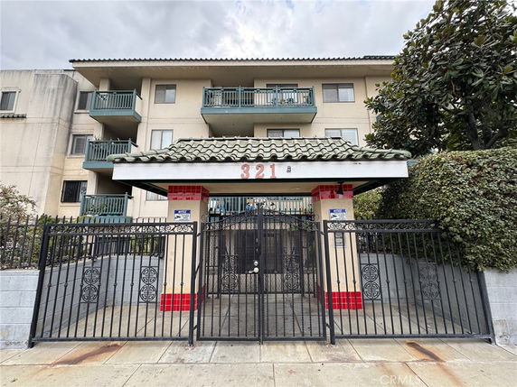 Front view of a multi-story residential building with balconies and a gated entrance.