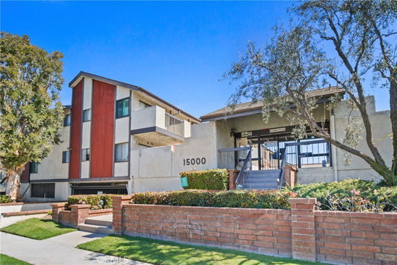 Front view of a multi-story building with balconies and distinct red paneling.