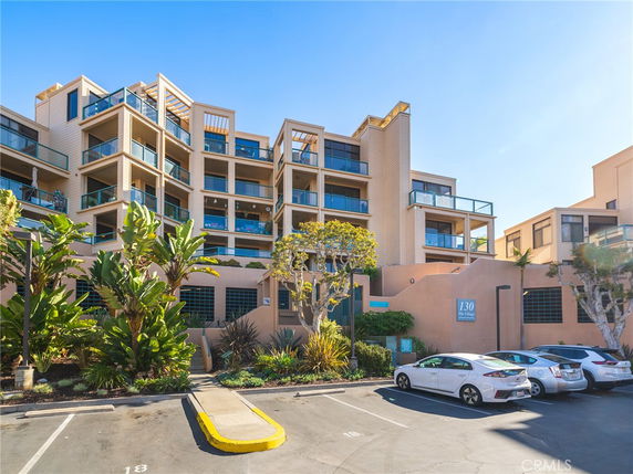 Front view of a modern multi-story residential building with balconies and glass railings.