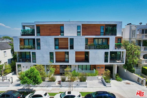 Front view of a modern multi-story building with balconies and wooden panel accents.