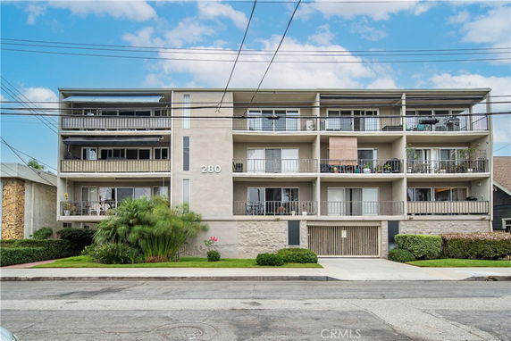 Front view of a multi-story apartment building with balconies and a garage entrance.
