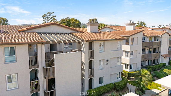 Front view of a multi-story apartment building with balconies and a tile roof.