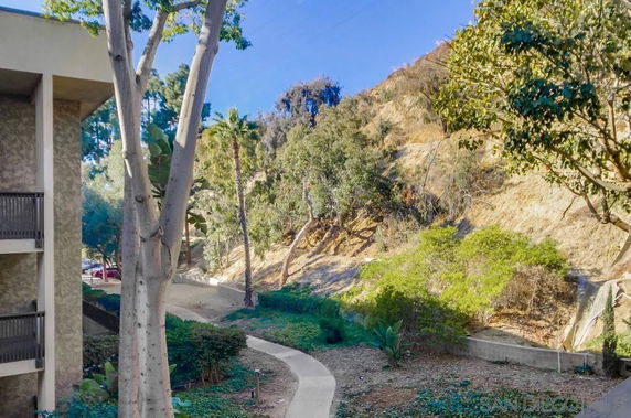 View of surrounding area with trees and a hillside near a building.
