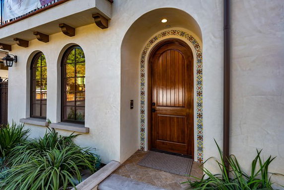 Front view of a house with an arched wooden door and decorative tiles.