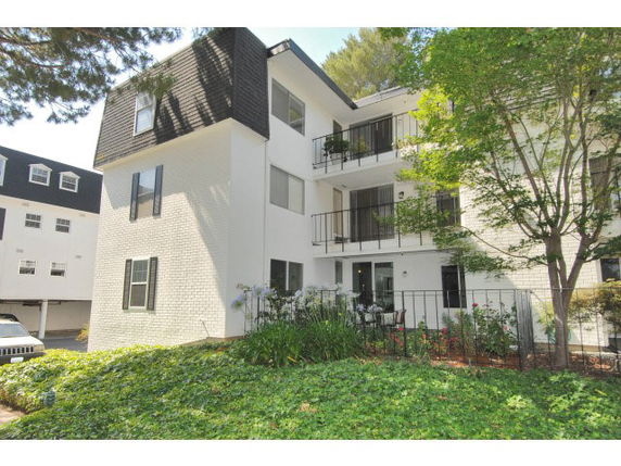 Front view of a multi-story building with balconies and black window shutters.