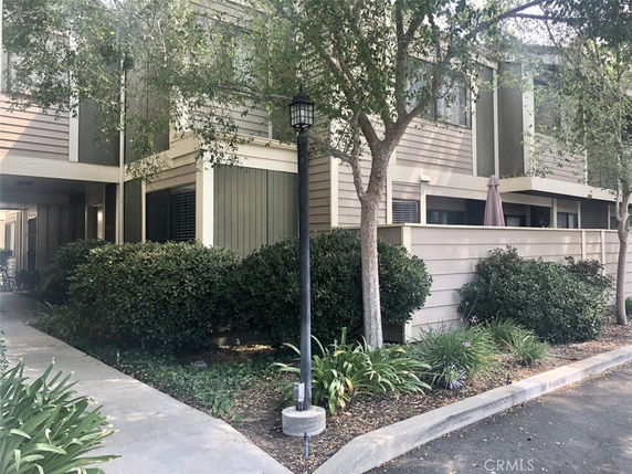 Front view of a two-story residential building with trees and shrubs nearby.