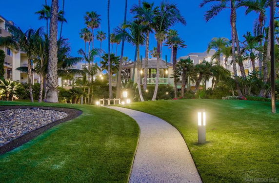 Evening view of apartment buildings with pathway and palm trees.