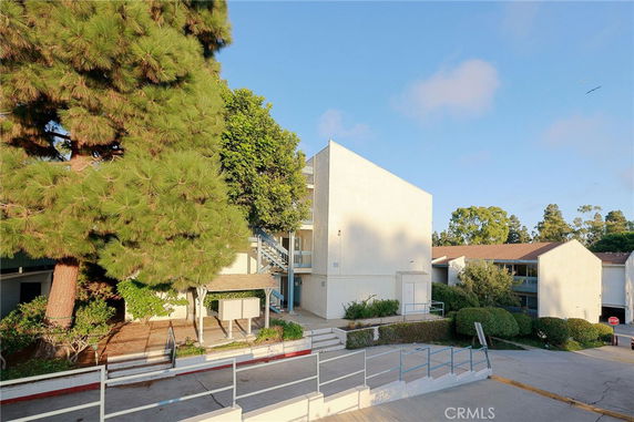 Front view of a multi-story apartment building with a flat roof and external staircase.