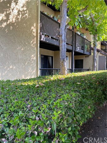 Front view of a multi-story building with balconies and greenery in front.