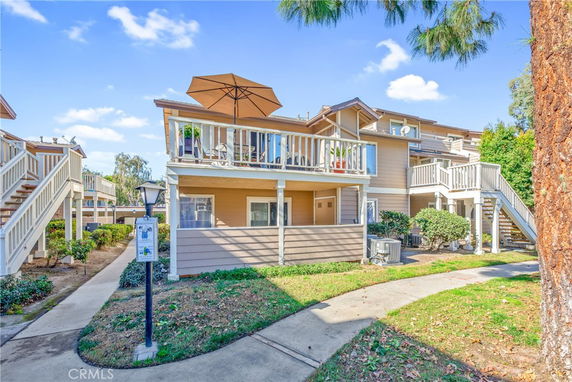 Front view of a two-story residential building with balconies and outdoor stairs.