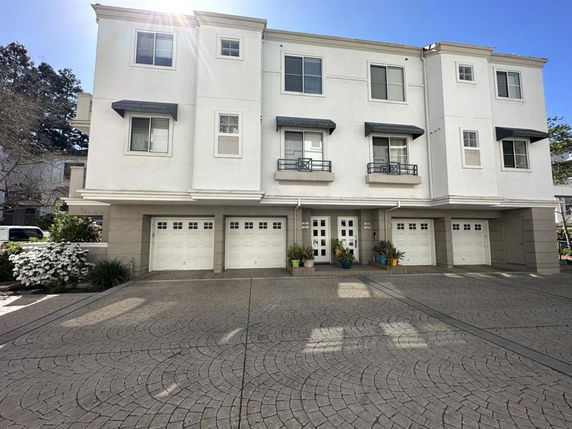 Front view of a three-story residential building with multiple garages and balconies.