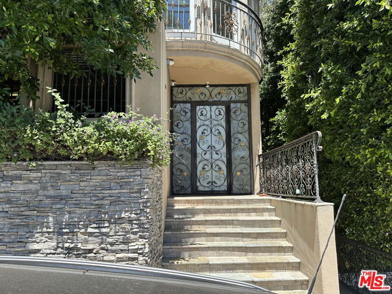 Front view of a house entrance with ornate iron doors and stone steps.